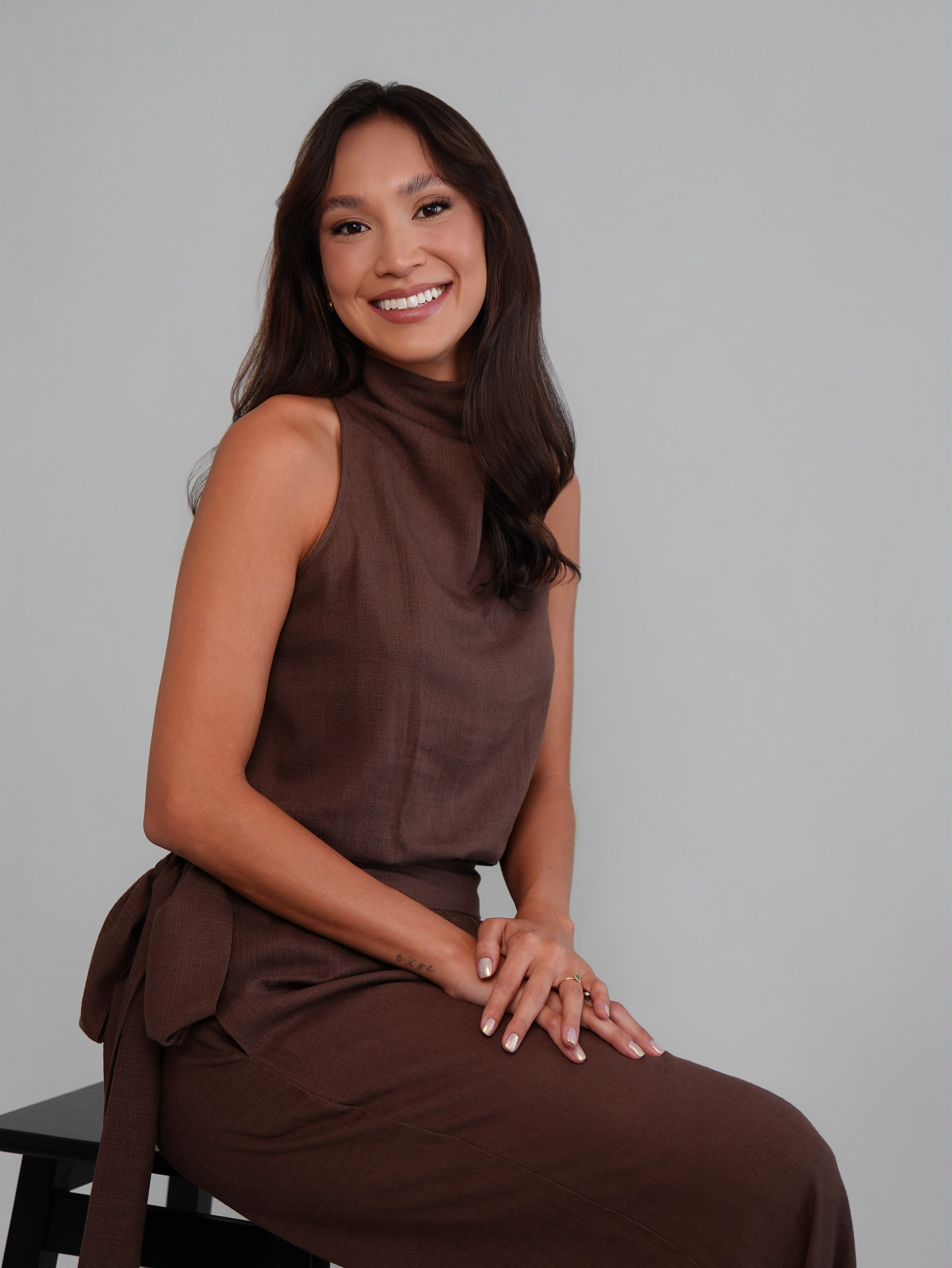 Ingrid Nozimoto sorrindo, sentada em um banco.