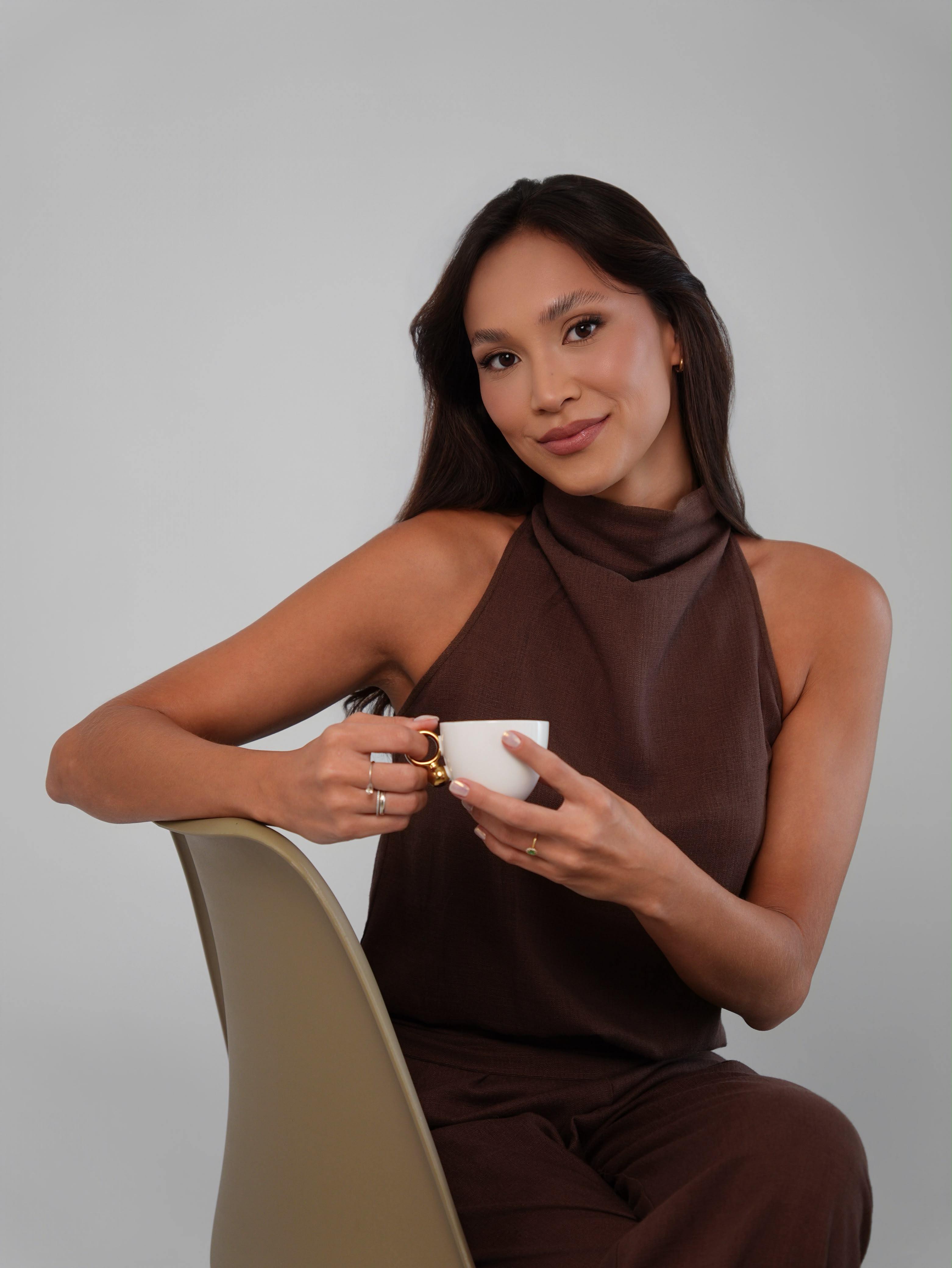 Ingrid Nozimoto sentada, segurando uma xícara, em retrato profissional.